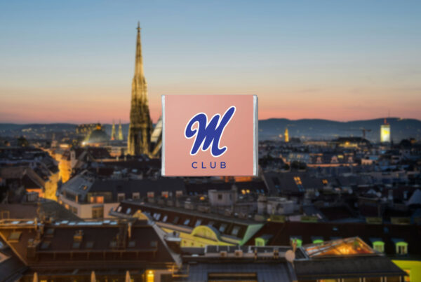 Verschwommenes Bild von Wien im Hintergrund, im Vordergrund das Logo des Manner Clubs